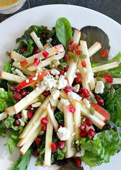 Apple salad with pomegranate seeds on white plate