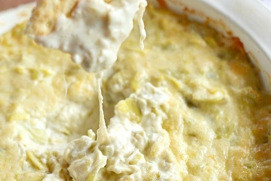 Close up of Artichoke Dip with a spoon stretching cheese