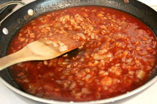 simmering sauce in a pan with a wooden spoon