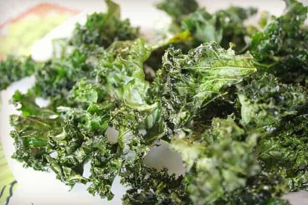 Baked Kale Chips close up on white plate 