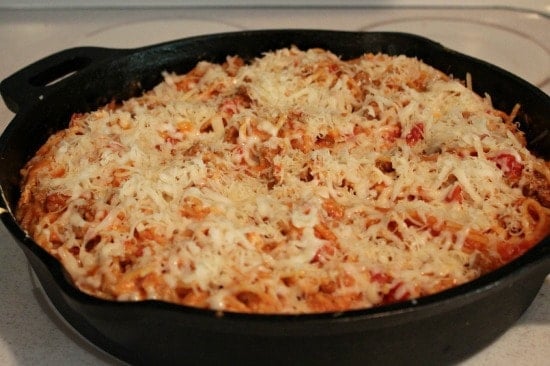 Skillet Baked Spaghetti with grated Parmesan on top ready to bake