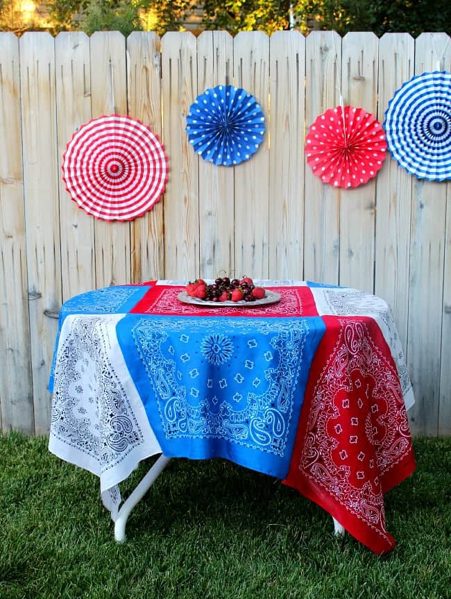 Red white blue tablecloth with decorative paper pinwheels on fence