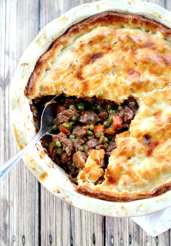 Beef pot pie with slice missing in white pie dish