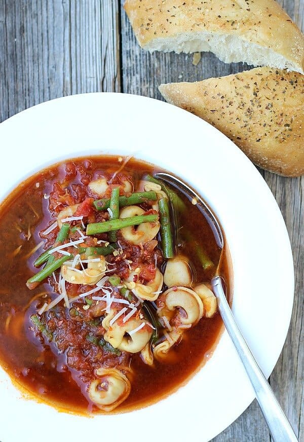 Beef tortellini soup with string beans, broth in white bowl