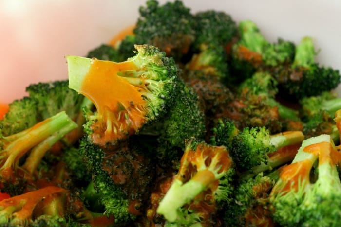 Broccoli drizzled with buffalo sauce after roasted