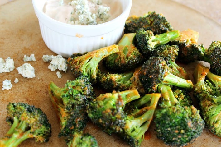 Buffalo Style Roasted Broccoli served with blue cheese dipping sauce on a brown plate