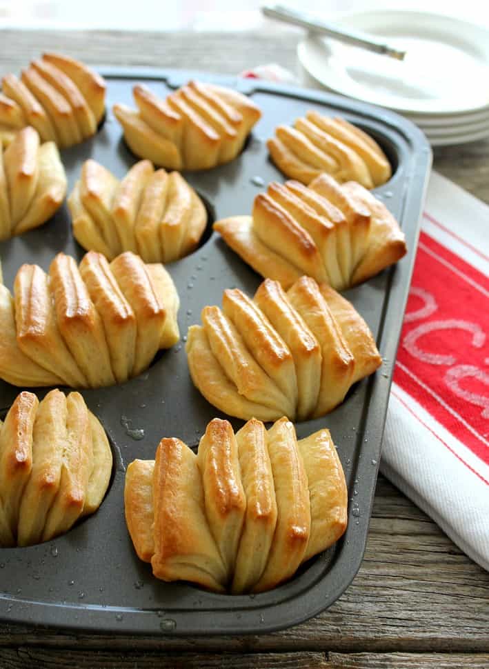 Butter Fan Rolls in muffin tin after baked with red and white napkin on side
