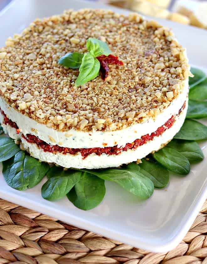 Cheese, Basil and Sun-Dried Tomato Torte on a white serving plate