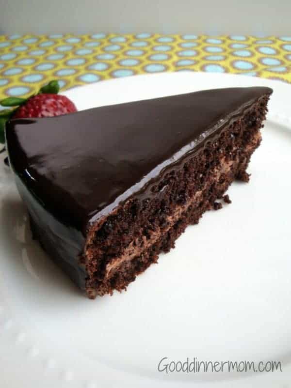 Gluten Free Chocolate Cake slice served on a white plate with a strawberry on the side