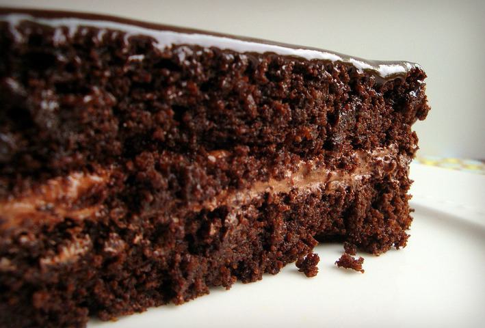 One slice of chocolate cake, side view on a white plate