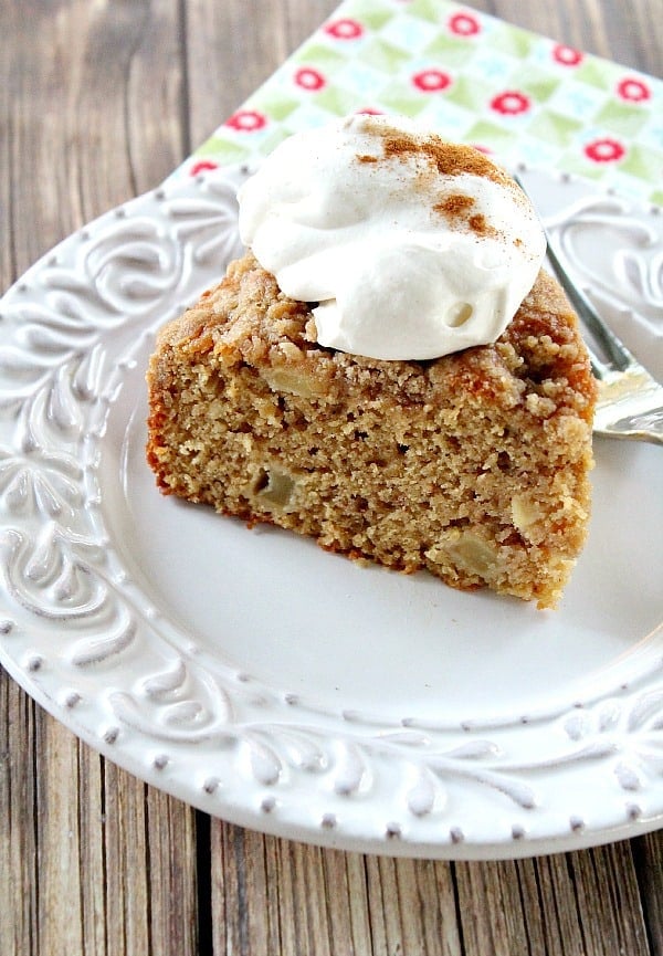 Cottage Apple Spice Cake slice topped with whipped cream on white plate