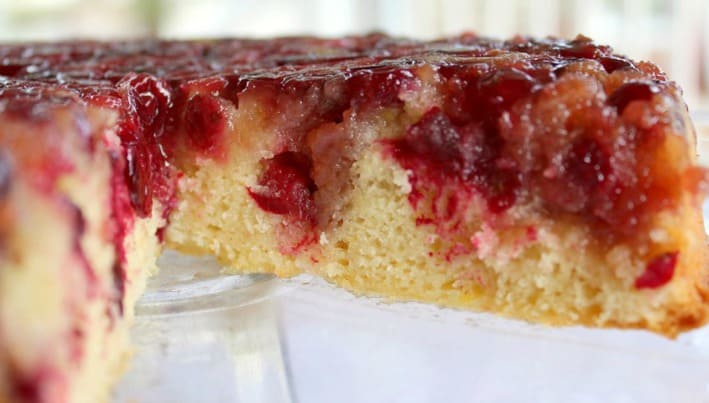 Cake with cranberries on top with a slice taken out