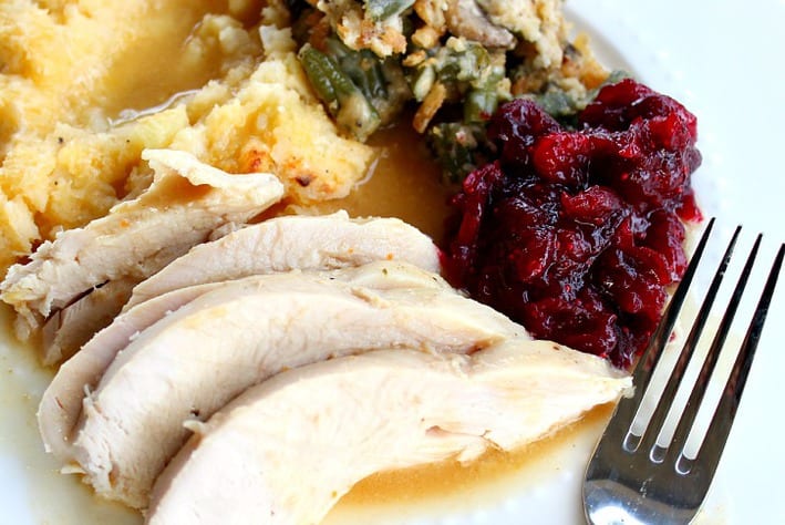 sliced turkey and mashed potatoes with cranberry sauce on a plate