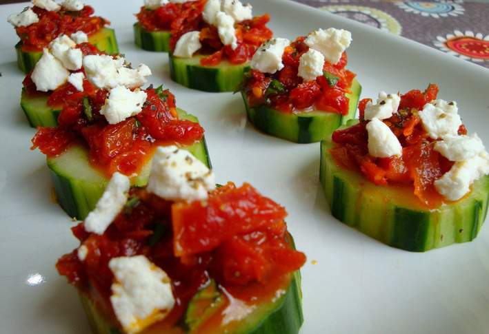 Sun-dried tomatoes and feta on cucumbers served on a white plate