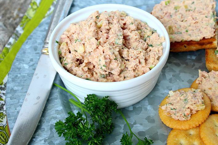Deviled ham spread in a white bowl with topped crackers and toast on the side