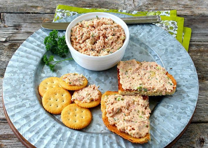 Deviled ham spread in a white bowl served with crackers and on toast on a tin plate. 