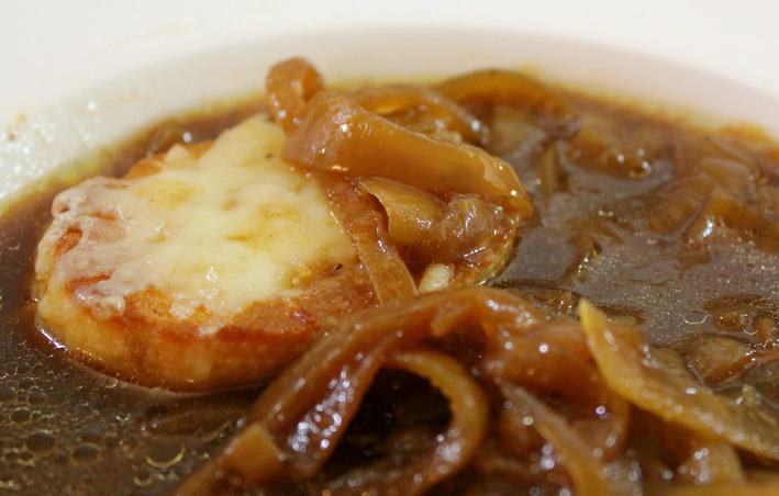 close up of French Onion Soup with caramelized onions and cheese baguette 
