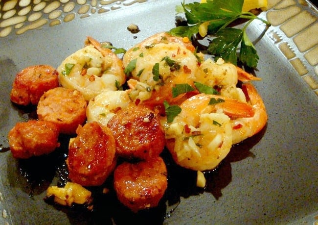 Garlic Shrimp served on a black plate with sausage 