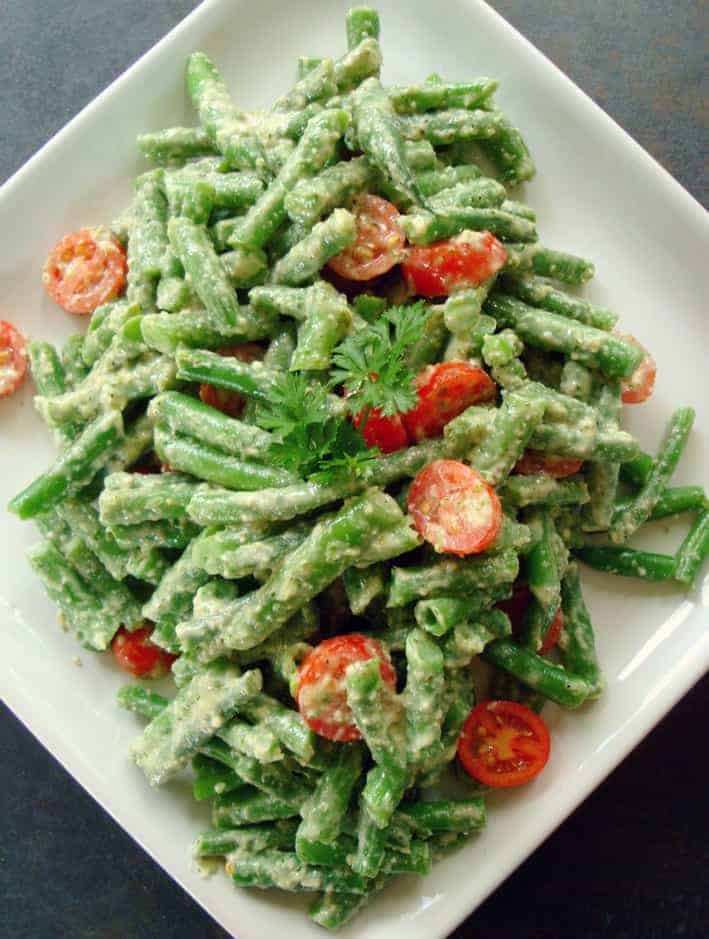 Green Beans in Dill Walnut Sauce with tomatoes on a white plate 