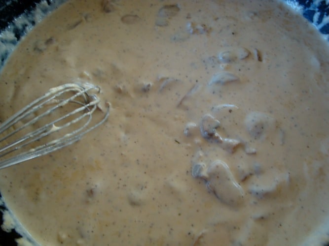sauce with mushrooms cooking in a pan with a whisk