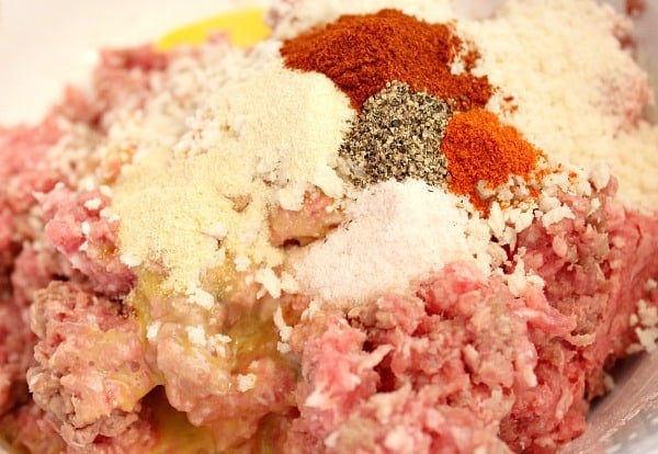 Raw meat and seasonings in a bowl, ready to be mixed