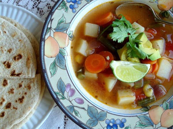 Top view of soup in a bowl served with tortillas on the side