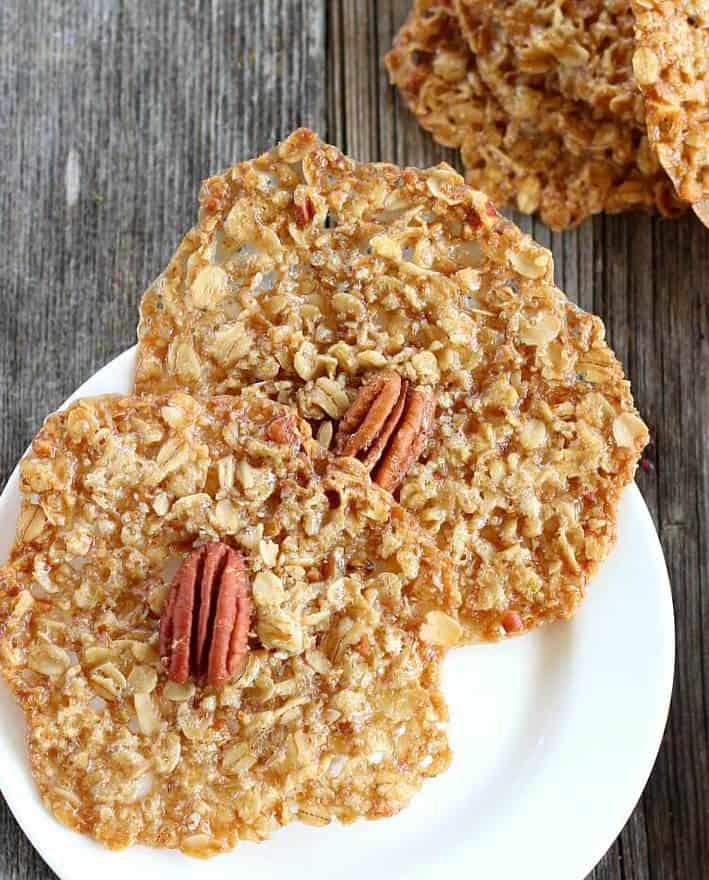 Oatmeal cookie crisps with pecan in center, two on a white plate