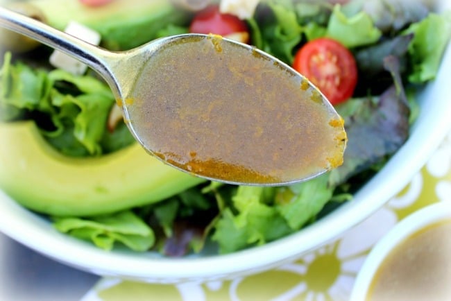 Orange Vinaigrette Salad Dressing on a spoon with salad in the background
