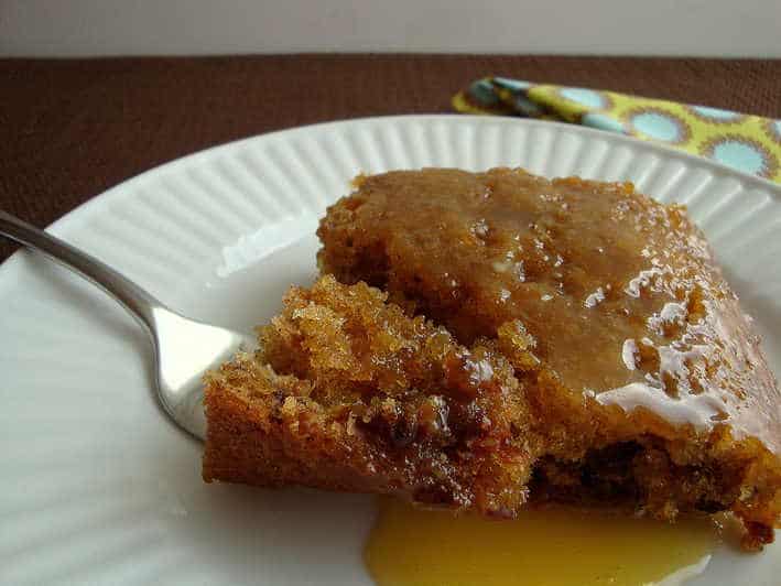 Prune cake with buttermilk glaze on a white plate with a fork