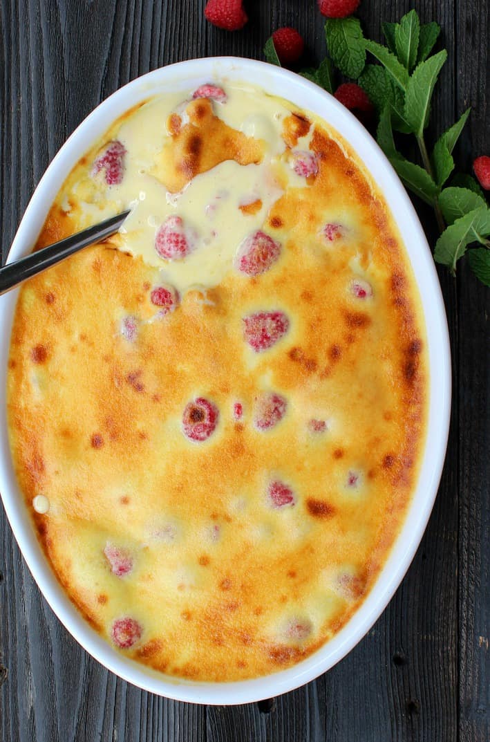 Raspberry Custard Gratin in a white baking dish with a spoon