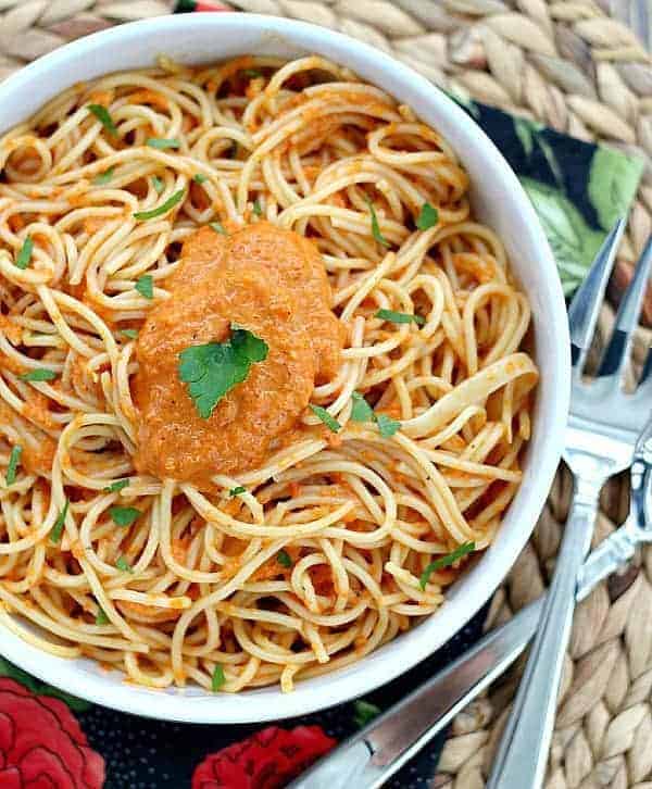 Red Pepper Pasta and Vegetable Sauce in a white bowl with fork and spoon on the side