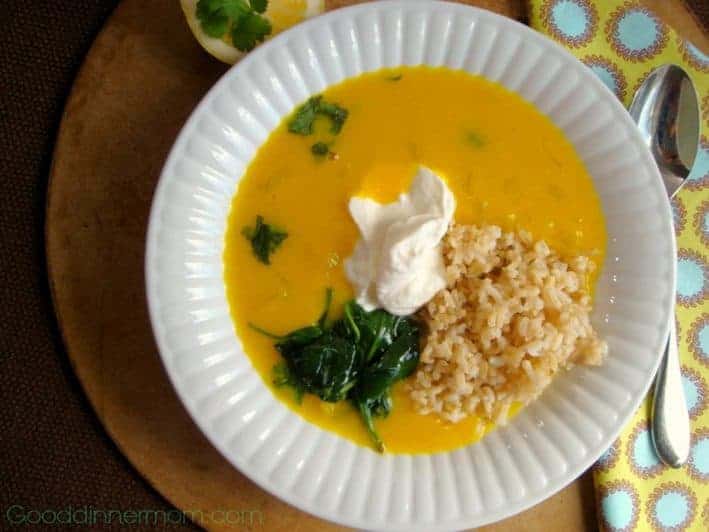 Red lentil and lemon soup with sour cream, spinach, and rice in a white bowl