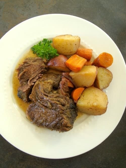 Chuck Eye Roast with potatoes, carrots and parsley on a white plate