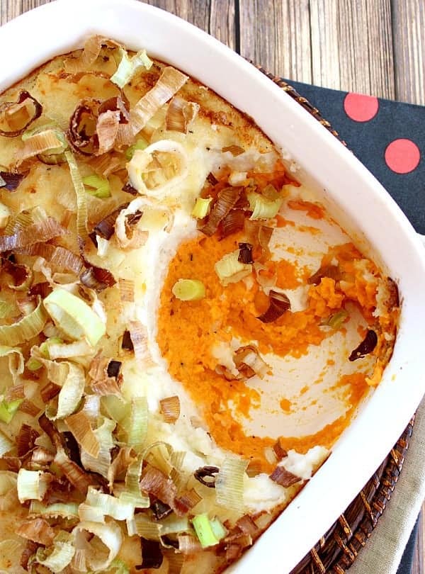 Russet and Sweet Potato Bake topped with crispy fried leeks in a white baking dish