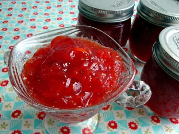 Strawberry and Grapefruit Marmalade in a glass bowl with jars of marmalade to the side