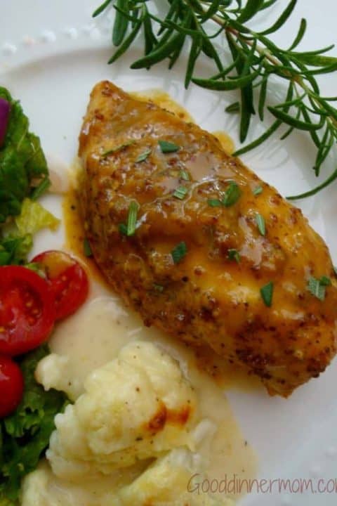 Sweet Mustard Chicken served with a salad and garnished with a sprig of thyme