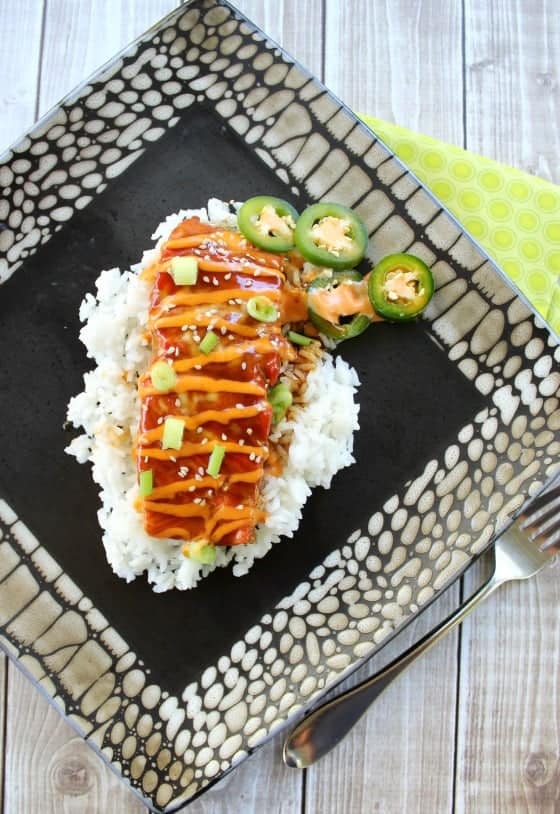 teriyaki salmon on rice on a plate with sliced jalapeños on the side