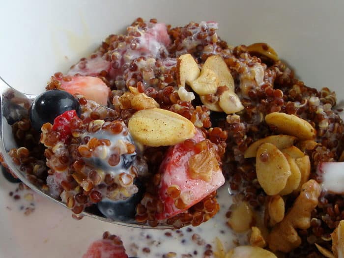 Close up of quinoa Breakfast in a bowl with berries and almonds and a spoonful 
