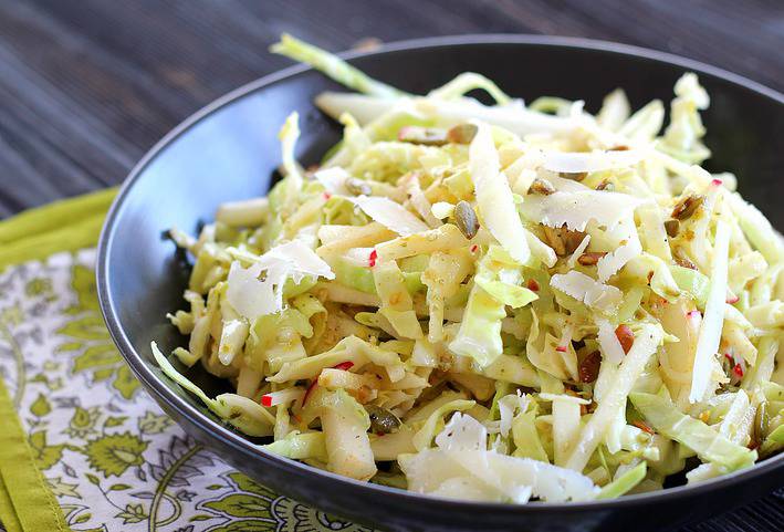 Side view of asian pear slaw in black bowl on green napkin 