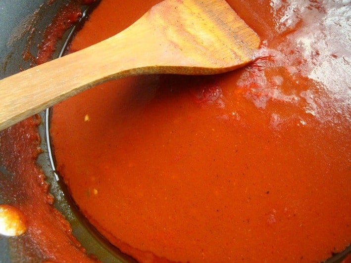Red sauce in pan with wooden spoon