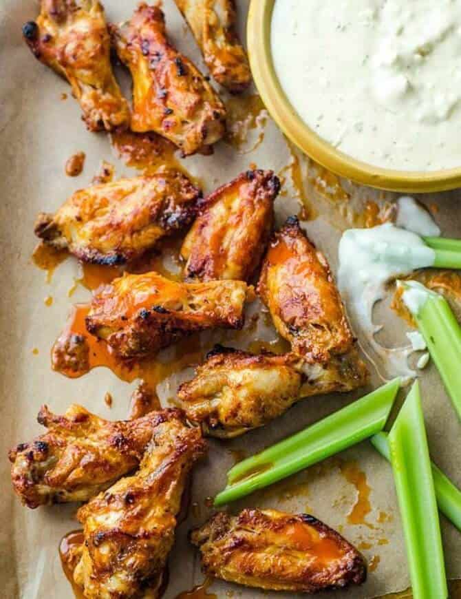  Ultimate Chicken Wing on parchment with celery and blue cheese dipping sauce on the side