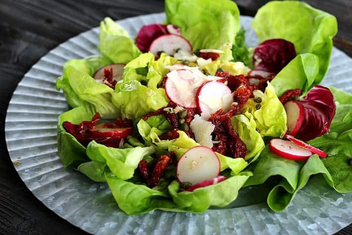 Butter Blossom Lettuce Salad with radishes and sun dried tomatoes on a tin plate