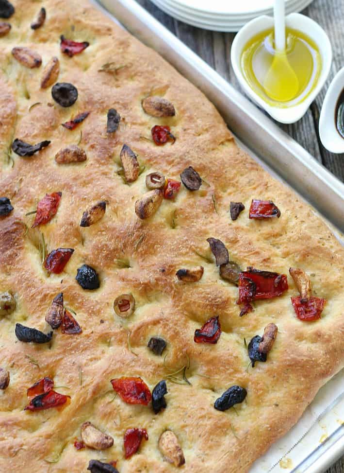 Focaccia bread on a baking sheet before cutting with olive oil on the side