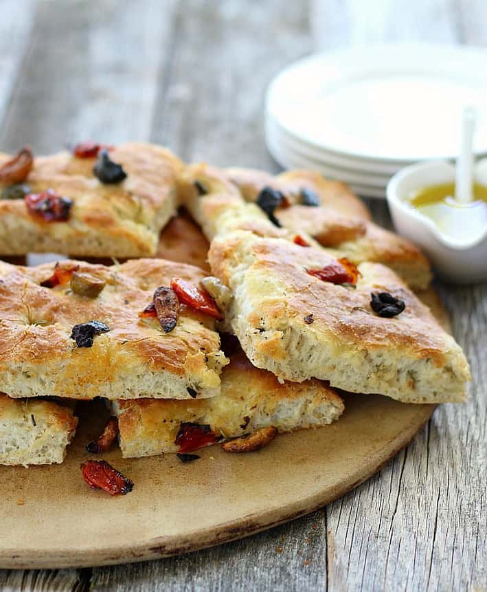 Focaccia Bread with Olives and Rosemary cut up on a serving plate