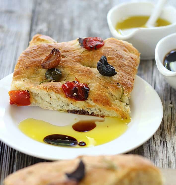 one slice of focaccia bread with a drizzle of olive oil and balsamic on a white plate