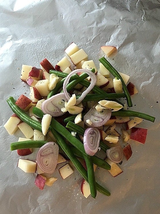 uncooked chopped potatoes, beans, garlic and shallots on foil 