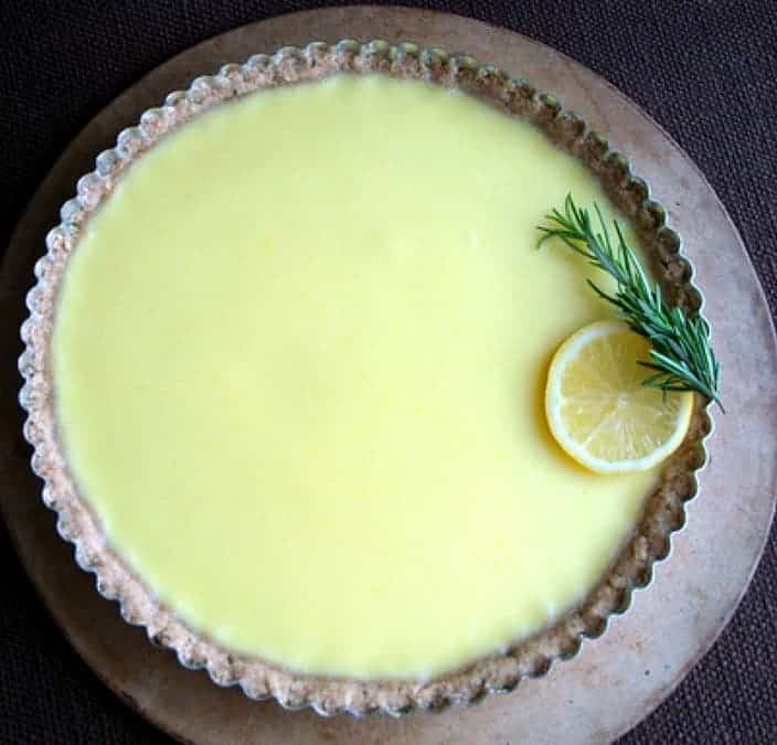 Lemon Tart with Rosemary Crust garnished with a slice of lemon and rosemary 