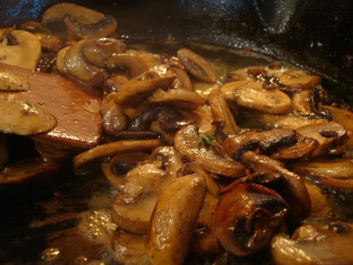 mushrooms cooking in a skillet with broth added